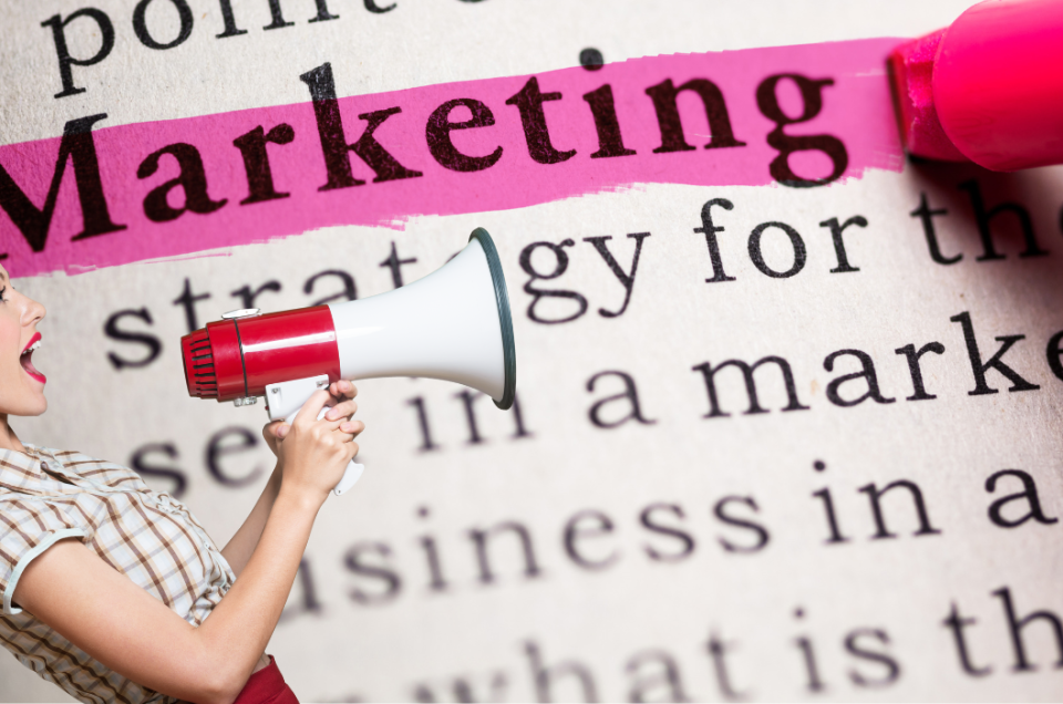 A woman holding a megaphone shouts, with the word “Marketing” highlighted in pink on a printed page in the background—captured in striking photography.
