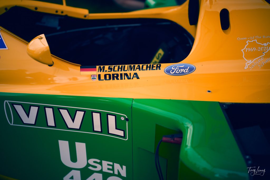 Close-up photography of a green and yellow racing car featuring the names M. Schumacher and Lorina with a Ford logo, plus sponsor decals like VIVIL. The cockpit and part of the bodywork are clearly visible.
