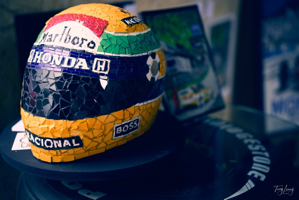 A mosaic art piece of a racing helmet with Marlboro, Honda, and Nacional logos in yellow, green, black, and white tiles, displayed on a round surface with blurred posters in the background.