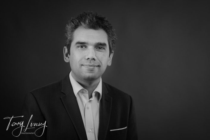 Intu Headshots - A man in a suit poses for a professional portrait against a plain studio background.