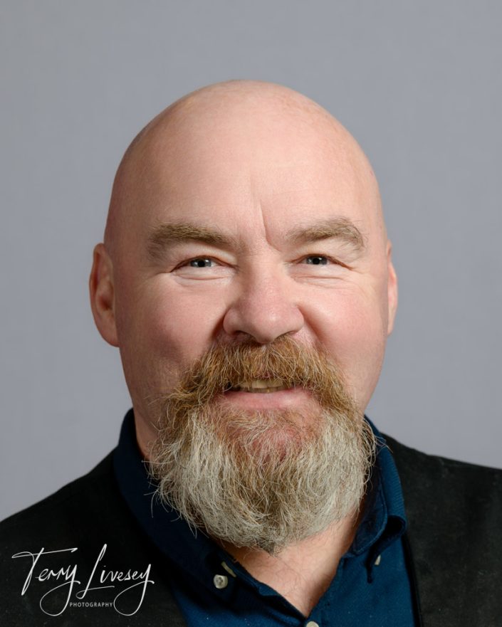 BMTC Headshots - A bald man with a thick beard, wearing a dark shirt, poses for a professional headshot portrait.