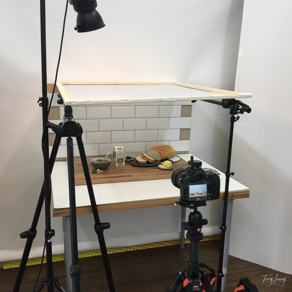 BTS shot showing using a scrim for a kitchen scene with the light above it so that it gets a soft light coming down.