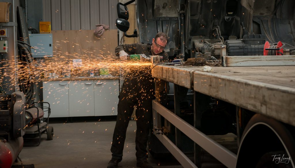 Man using an angle grinder on a truck flat bed