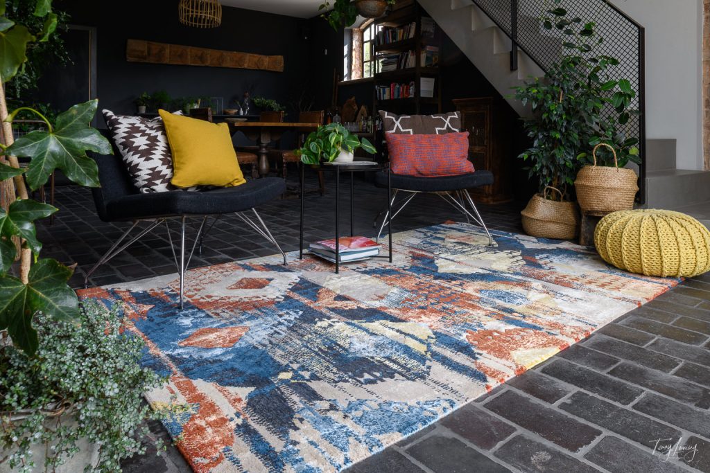 A rug placed in a prominent place of the room with all other furniture around it.