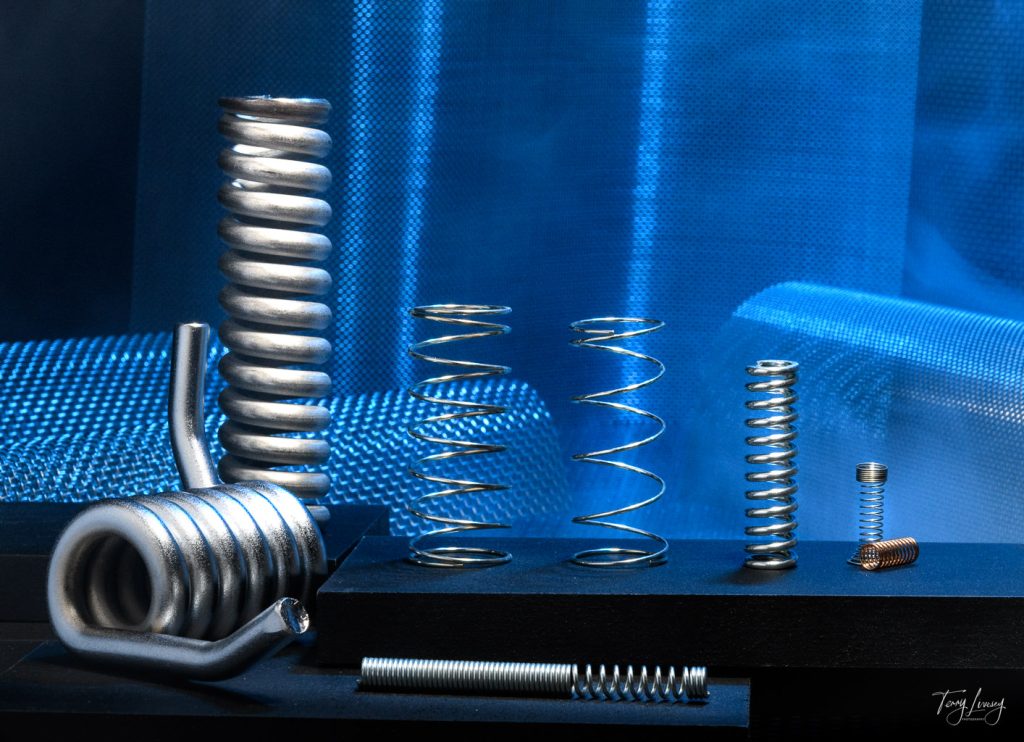 Metal springs on wooden blocks with a steel mesh background lit with a blue light.