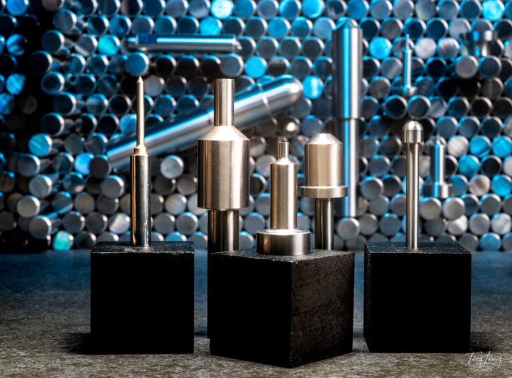 Tungsten carbide tooling parts setup with a scene of blank rods in the background. A blue light is lighting the background.