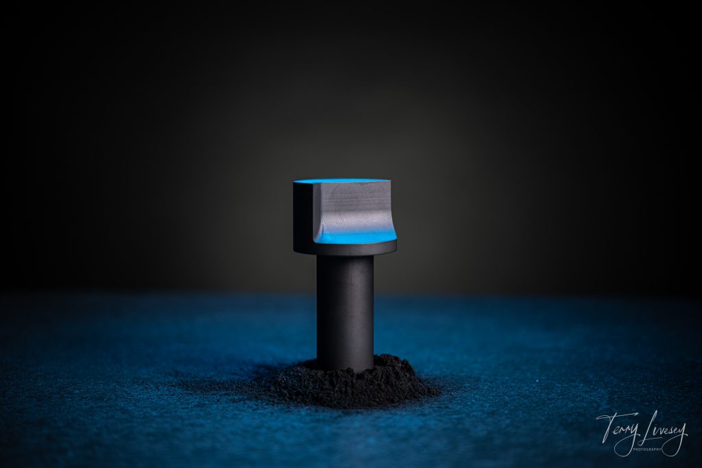 A tooling part in carbon with a textured base and clean black background