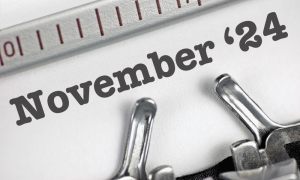 Close-up of the words 24 November typed on white paper with a typewriter, with part of the typewriter's metal components and ruler visible.