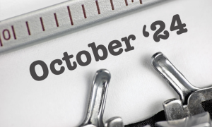 Close-up of the words 24 October typed on white paper in a typewriter, with parts of the metal typewriter mechanism visible.