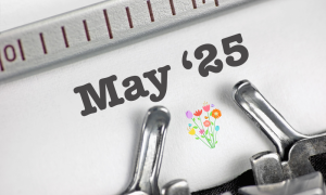 The image shows the words 25 May in bold text with a small colourful flower illustration below, set against a white background with part of a typewriter visible.