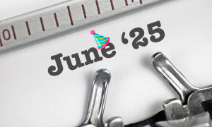 A close-up of a typewriter with the text 25 June in bold letters, featuring a colourful party hat graphic above the letter u.