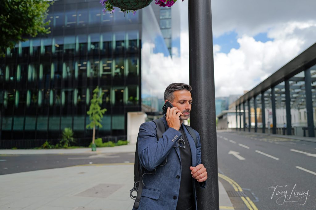Male model using a mobile phone leaning against a lamp post