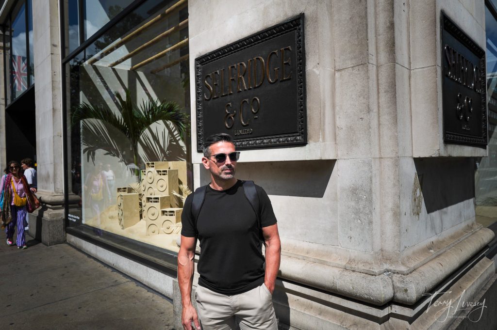 Male model standing in front of the Selfridge & CO sign in London
