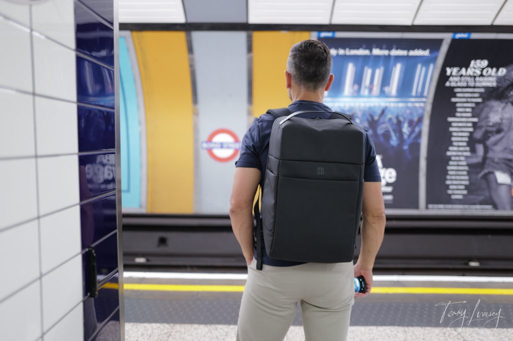 Male model from behind with a PW3R backpack waiting for a tube train in London