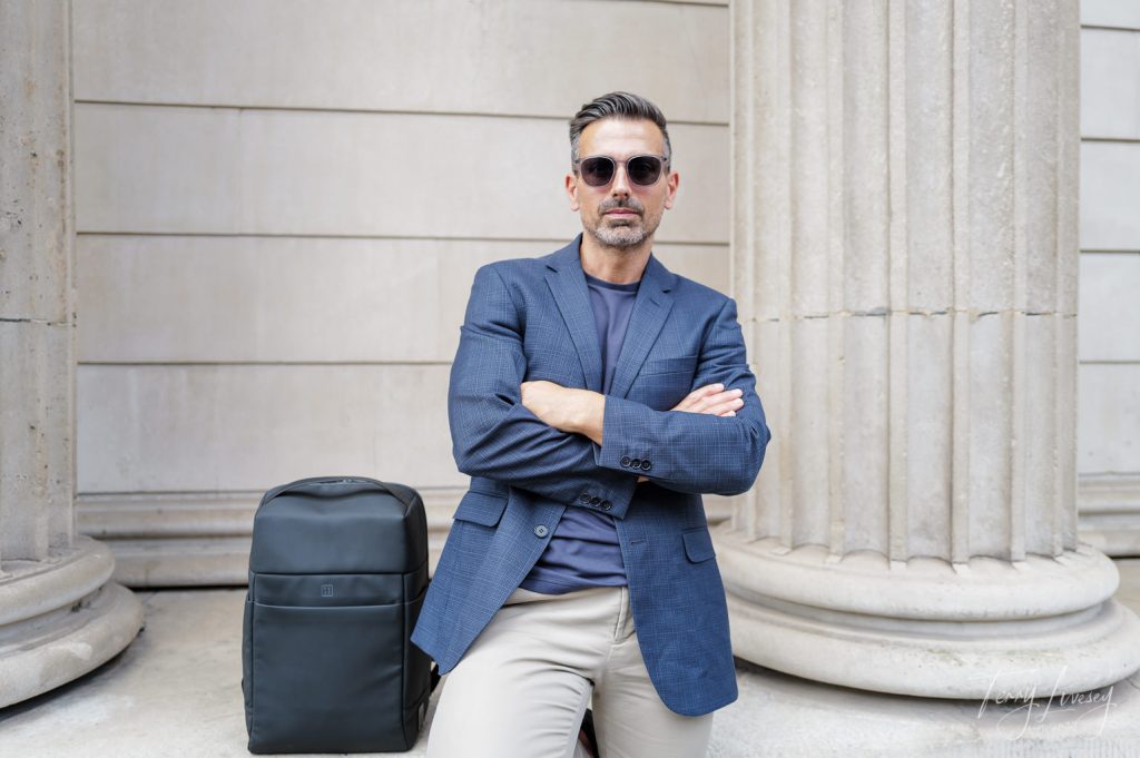 Male model with folded arms next to PW3R backpack