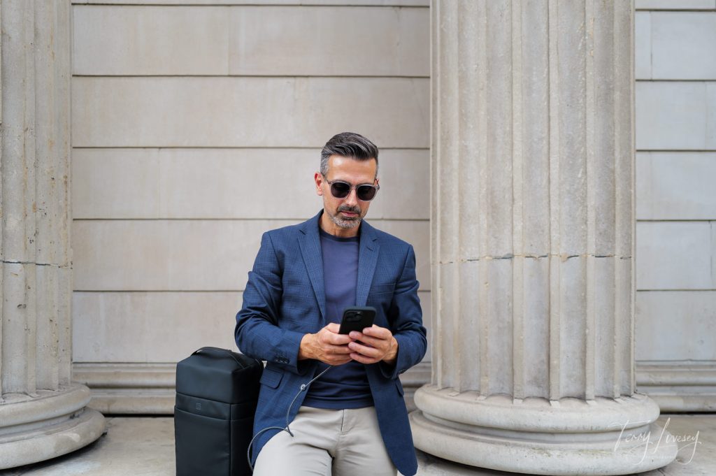 Male model looking at phone with a PW3R backpack by his side