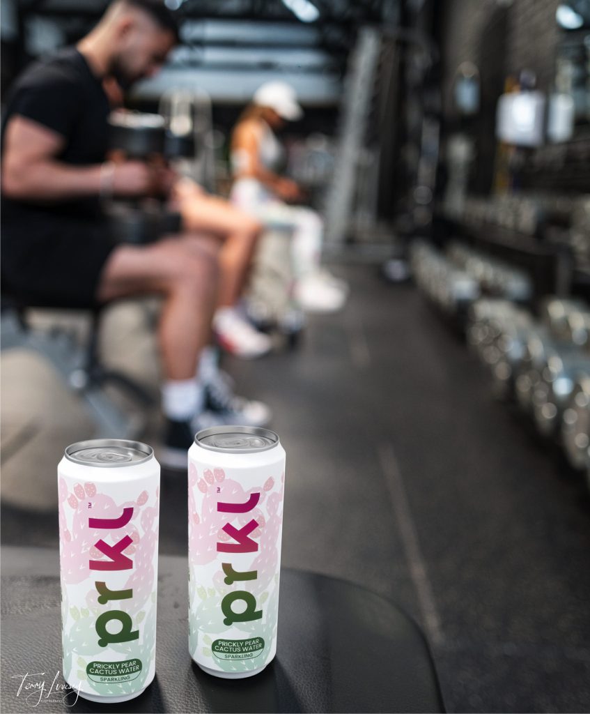 Woman and man blurred out in background at gym with PRKL can in foreground for a product shot