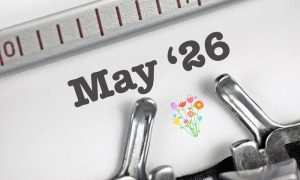 26 May typed on white paper with a small colourful bouquet illustration, shown in close-up between the typebars and ruler of a typewriter.